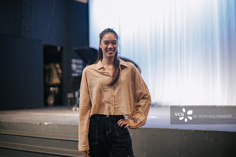 自信的年轻亚洲女性在剧院舞台上微笑图片素材