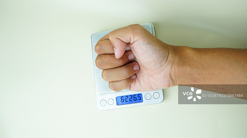 拳头放在数字秤上测量，力量的理念静态展示图片素材