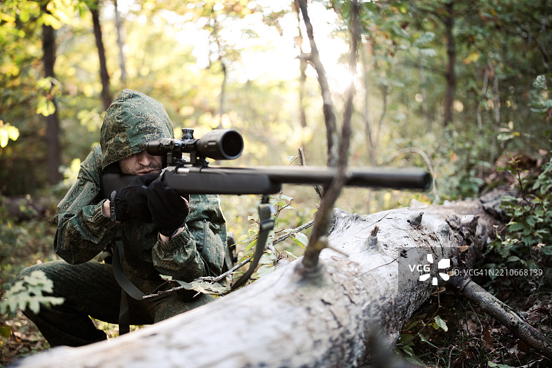 身穿战术装备的士兵在森林地区瞄准步枪。图片素材