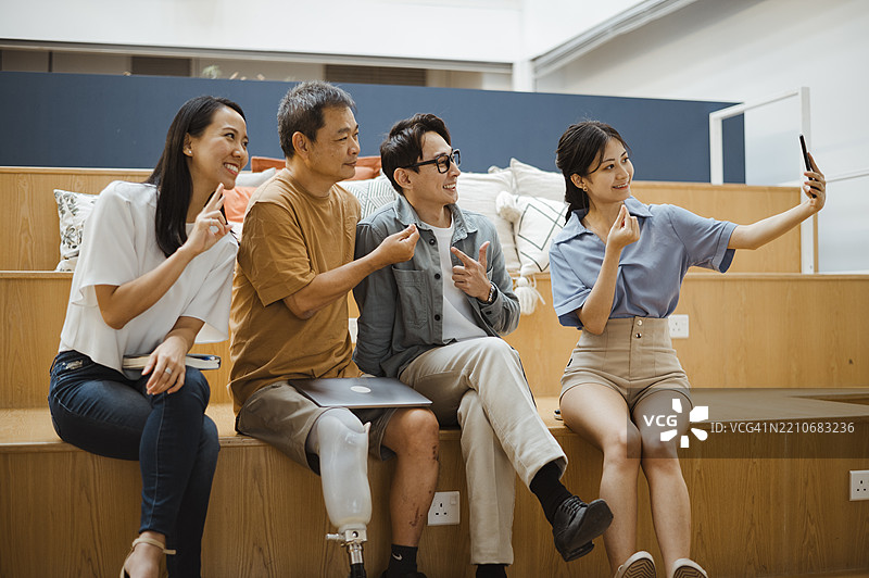 庆祝团队精神：办公室团队自拍与残疾专业人士图片素材