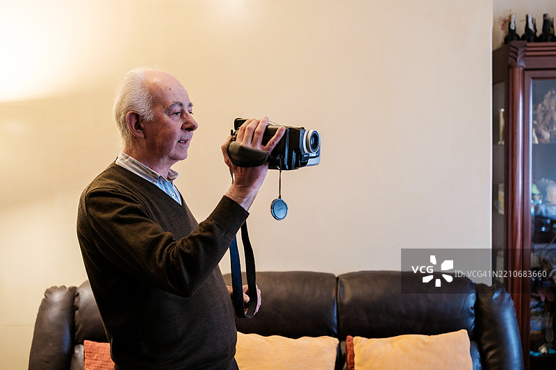 老年人在客厅用旧摄像机录制视频图片素材