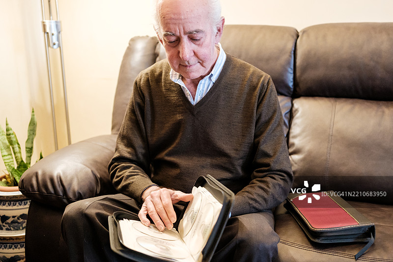 老年人在家中浏览他的CD收藏图片素材