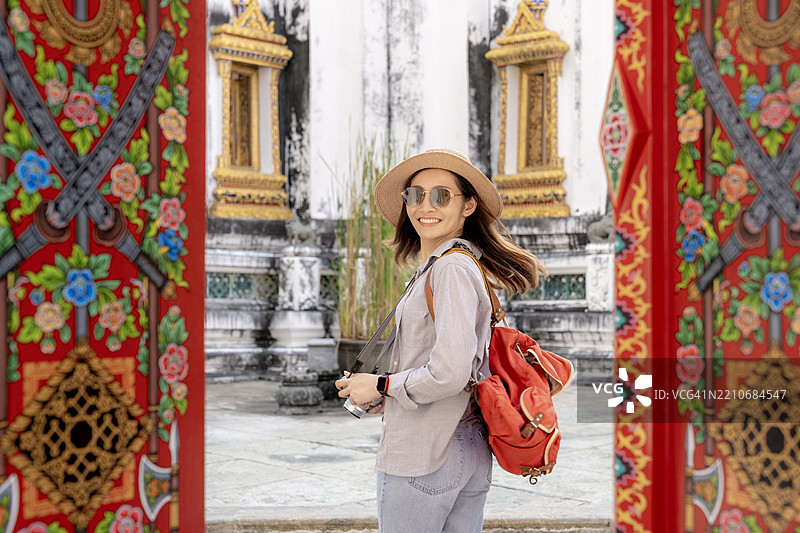 一位年轻女性游客在泰国曼谷探索时用智能手机自拍图片素材