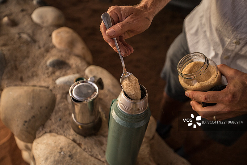 在装满黑咖啡的保温瓶中倒入糖图片素材