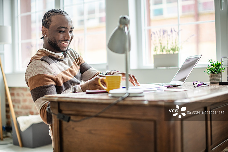 年轻男子在家上网课，同时享受一杯咖啡，促进高效学习和生产力图片素材