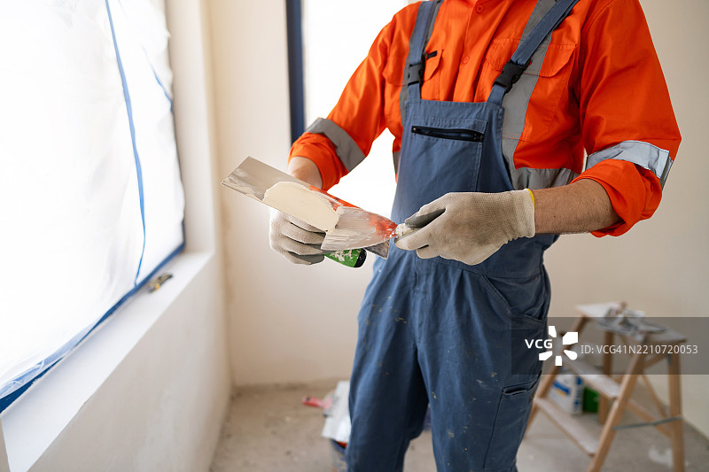 工人在房间装修时将腻子涂抹在墙上图片素材