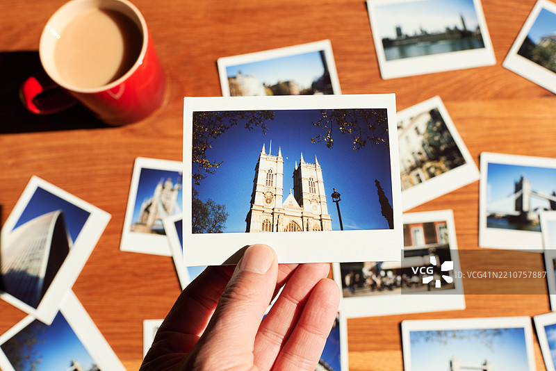 男人在桌子上整理他的伦敦旅行度假照片集。图片素材