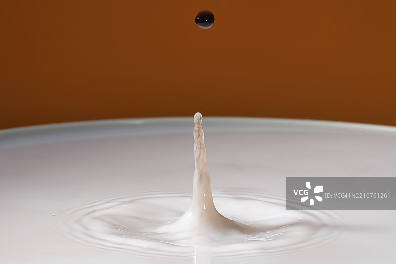 一滴水落在平静的水面上，背景为橙色，水滴，碰撞，高速摄影，概念，图形图片素材