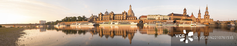 德累斯顿，卡罗拉桥、布吕尔平台、美术学院、圣母教堂、文理中学、议会大厦、格奥尔格门、哈乌斯曼塔楼、宫廷教堂和奥古斯都大桥在晨光中的城市天际线全景，埃尔布河倒影图片素材