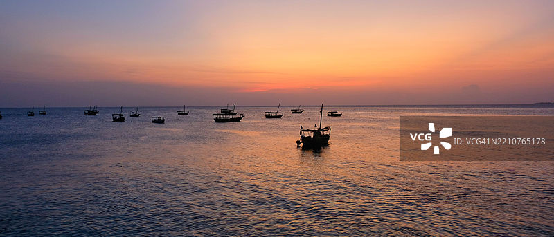 日落时分，海面上的船只剪影与天空相映成趣图片素材