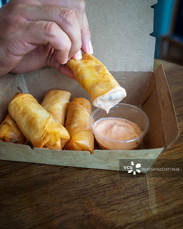 装在棕色外卖盒中的炸春卷，配有奶油酱图片素材