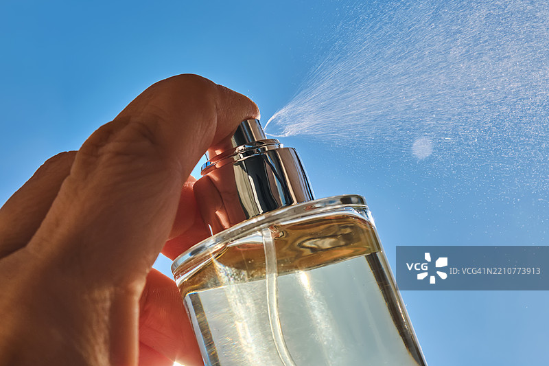 手握瓶子，背景是蓝天图片素材