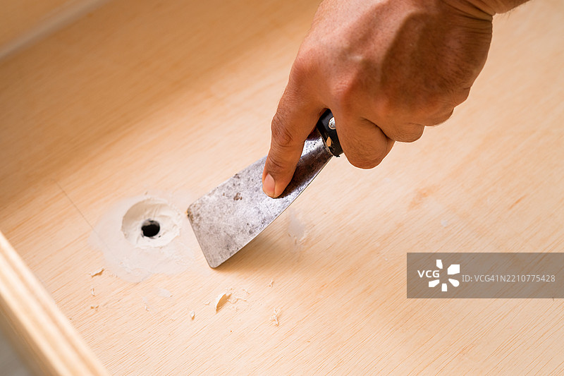 手持刮刀工具，刮去白色油漆图片素材