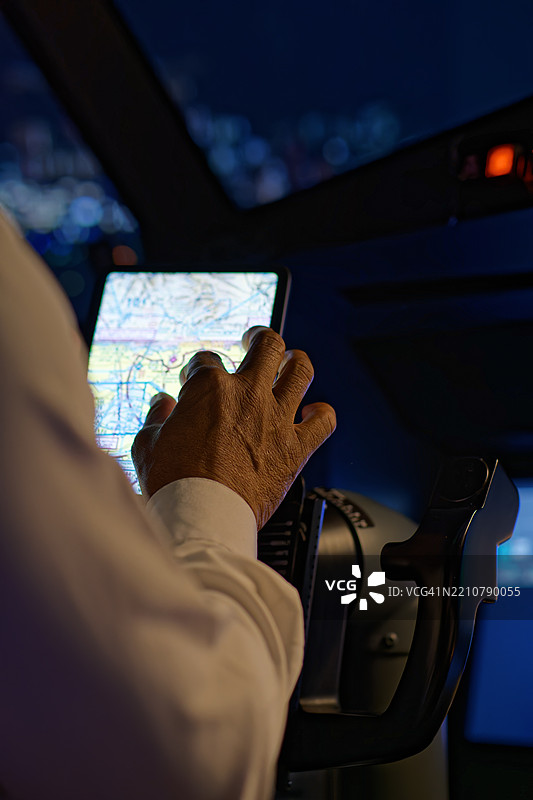 飞行员在客机驾驶舱内查看平板电脑上的航空图表图片素材