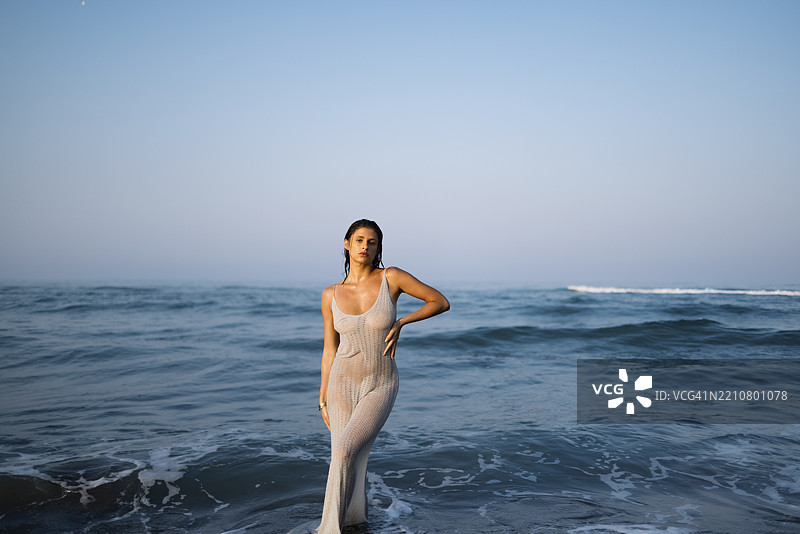 在清澈蓝色海洋地平线上优雅地摆姿势的女性图片素材