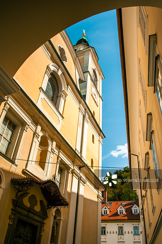 从下面俯视一座天主教教堂及其塔楼，塔楼上有一个宗教十字架，位于老城区。图片素材