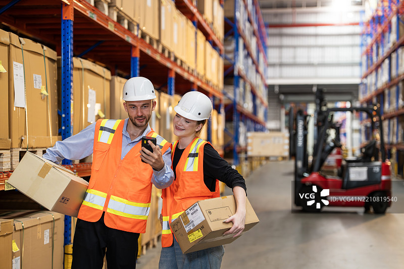 仓库工人在有序的储存设施中佩戴安全装备进行协作图片素材