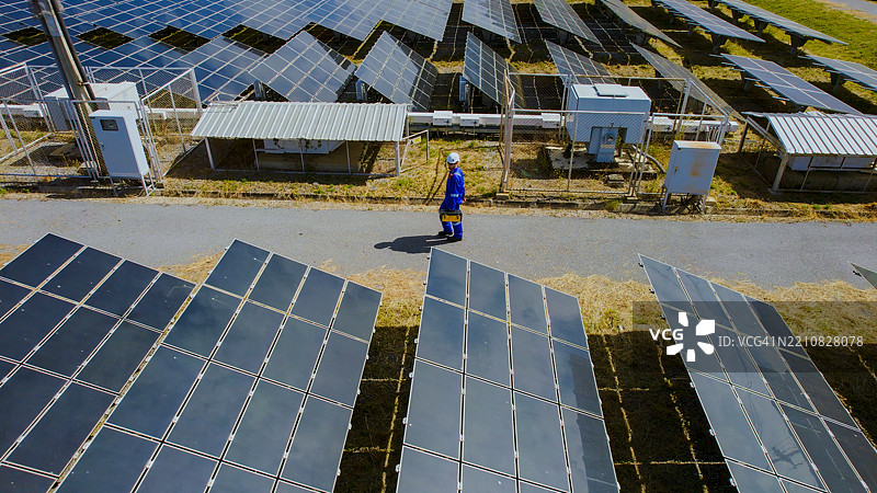 服务工程师在太阳能电站农场工作结束后沿路走的鸟瞰图。图片素材