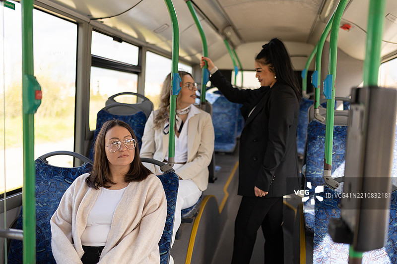 女人们在城市公交车上交谈和骑行。图片素材