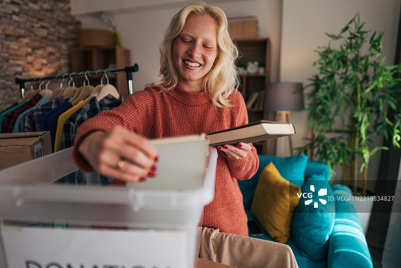 年轻女性向慈善机构捐赠衣物和书籍图片素材