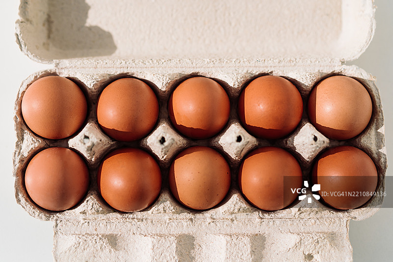 白色背景上装有新鲜棕色鸡蛋的纸 carton 顶视图图片素材