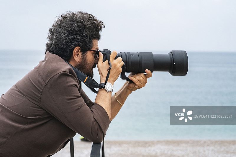男性摄影师在海滩上拍照图片素材