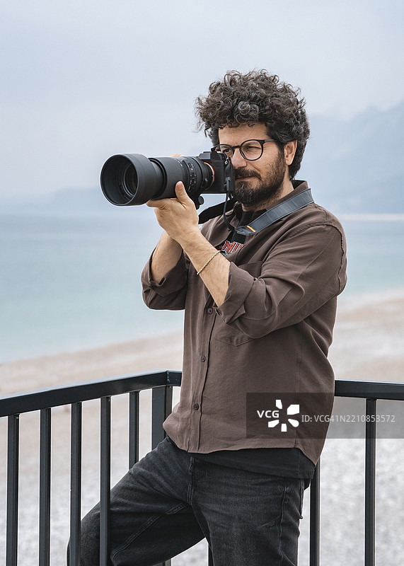 男性摄影师在海滩上拍照图片素材