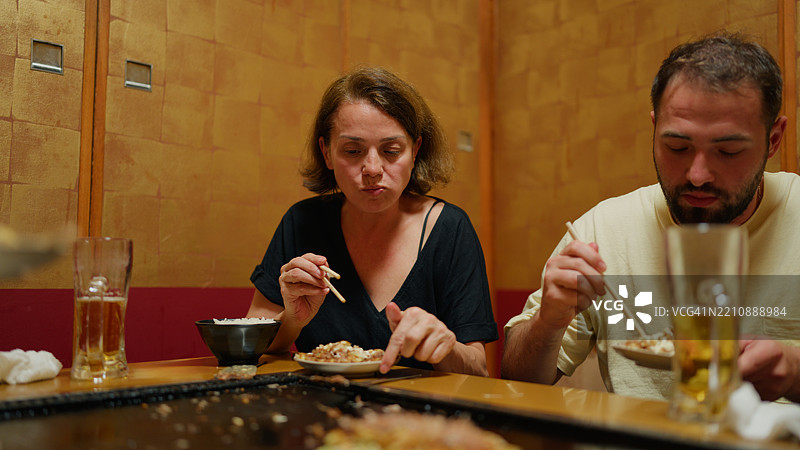 游客们在日本风格的居酒屋享受传统日本美食——大阪烧。图片素材