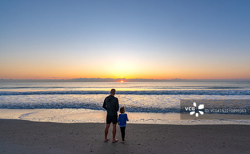 父亲和女儿在美国佛罗里达州中部的可可海滩享受生机勃勃的春日晨曦图片素材