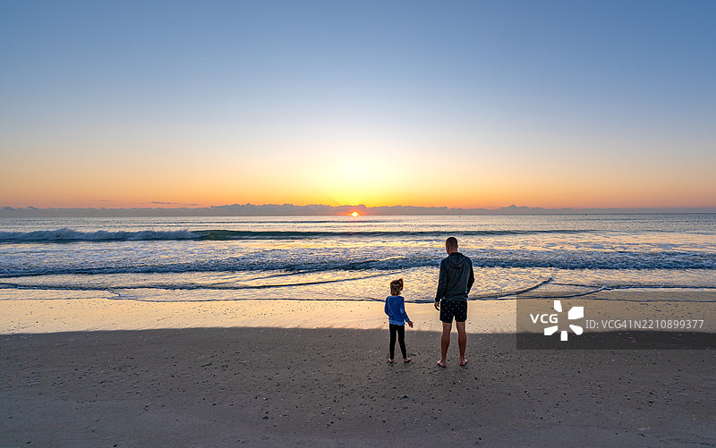 父亲和女儿在美国佛罗里达州中部的可可海滩享受生机勃勃的春日晨曦图片素材