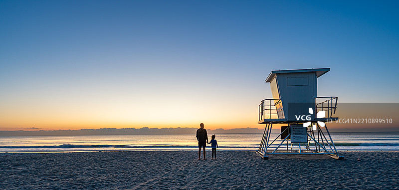 父亲和女儿在美国佛罗里达州中部的可可海滩享受生机勃勃的春日晨曦图片素材