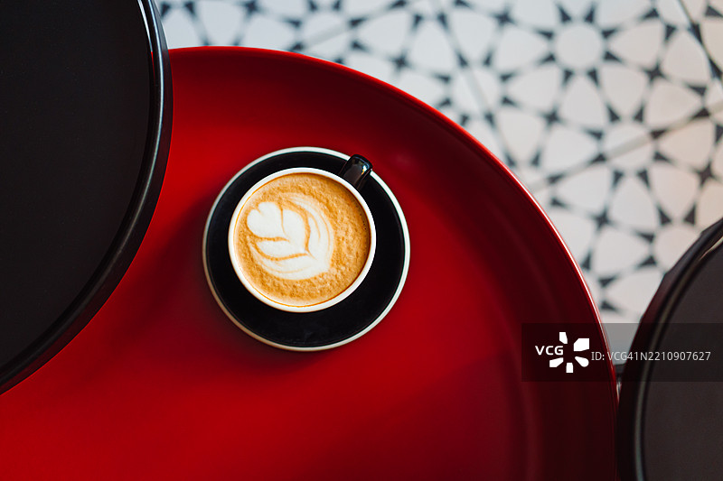 时尚红桌上的拿铁艺术卡布奇诺咖啡杯图片素材