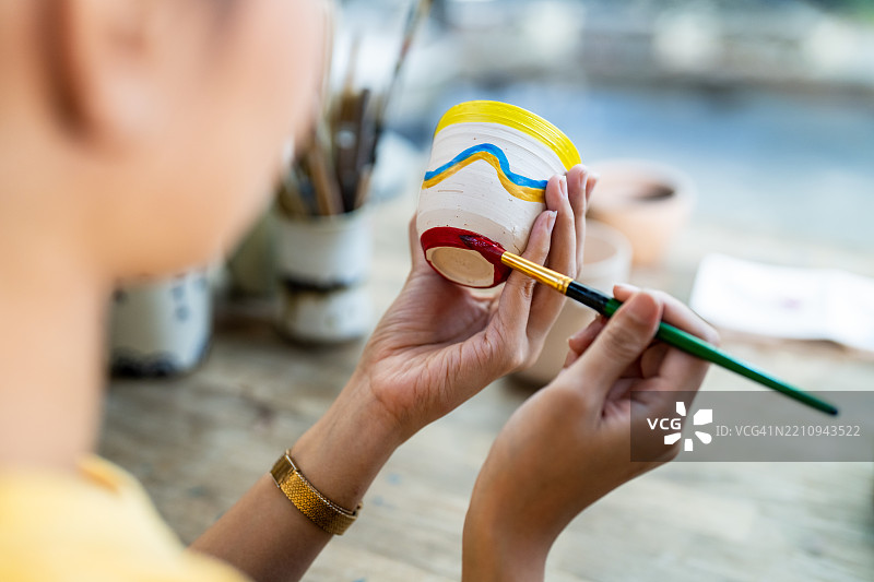 一个人在给陶瓷花盆绘制色彩斑斓的艺术图案图片素材