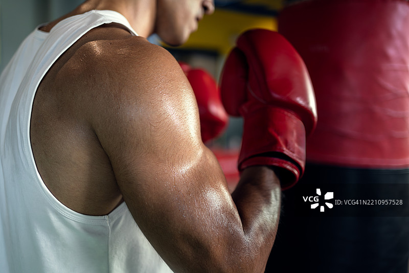 亚洲男性在健身房用沙袋练习拳击。图片素材