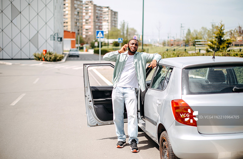 男子的轮胎漏气，正在使用手机请求帮助图片素材