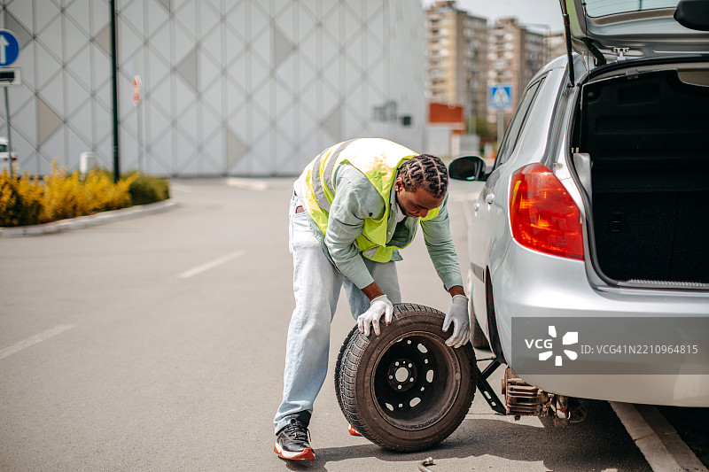 男子在给他的汽车换轮胎图片素材