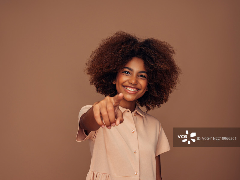 年轻女性在中性背景下微笑并指向前方图片素材