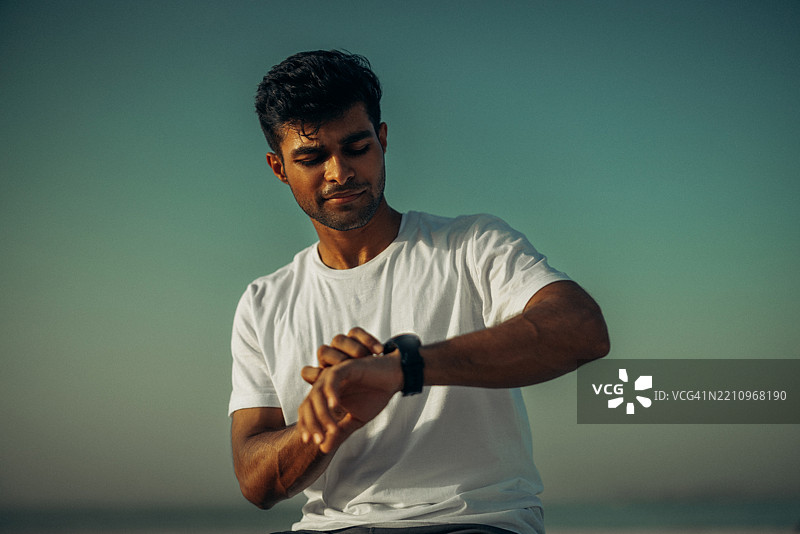 男人在宁静的户外时刻仰望天空，查看手表。图片素材