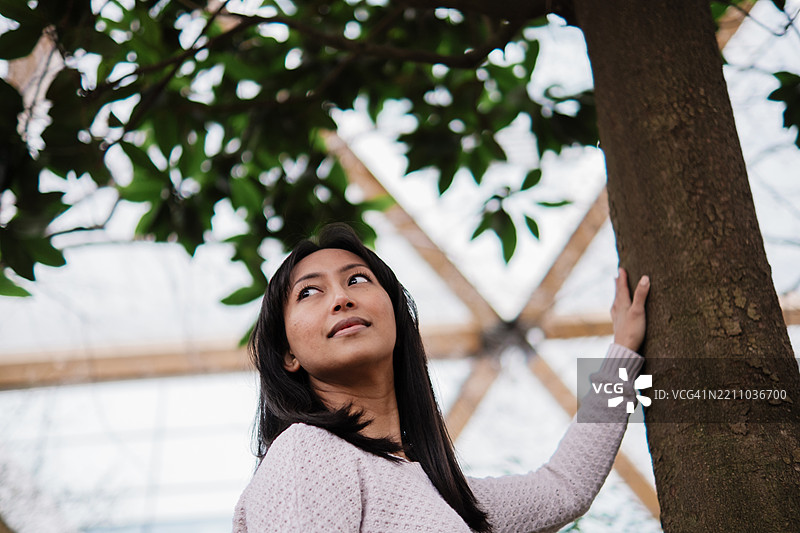 年轻的亚洲女性在植物园探索并触摸一棵树图片素材