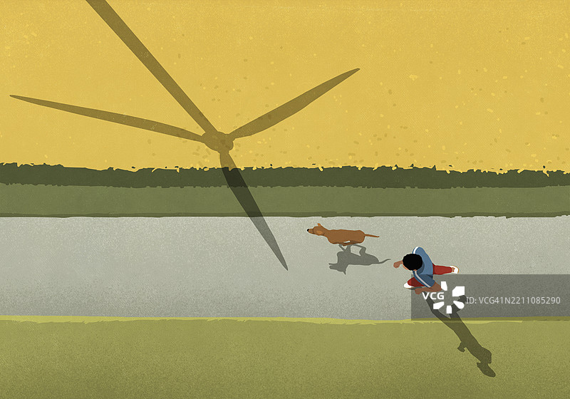 从上方俯瞰，男人和狗在田野小路上慢跑，身旁是风力发电机的影子。图片素材