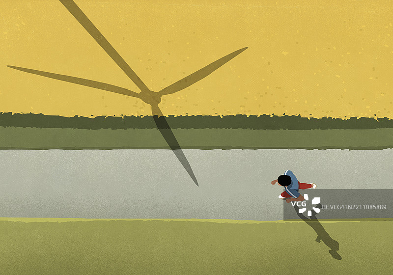 从上方俯瞰，男子在乡村田野的小路上慢跑，身旁是风力发电机的影子。图片素材