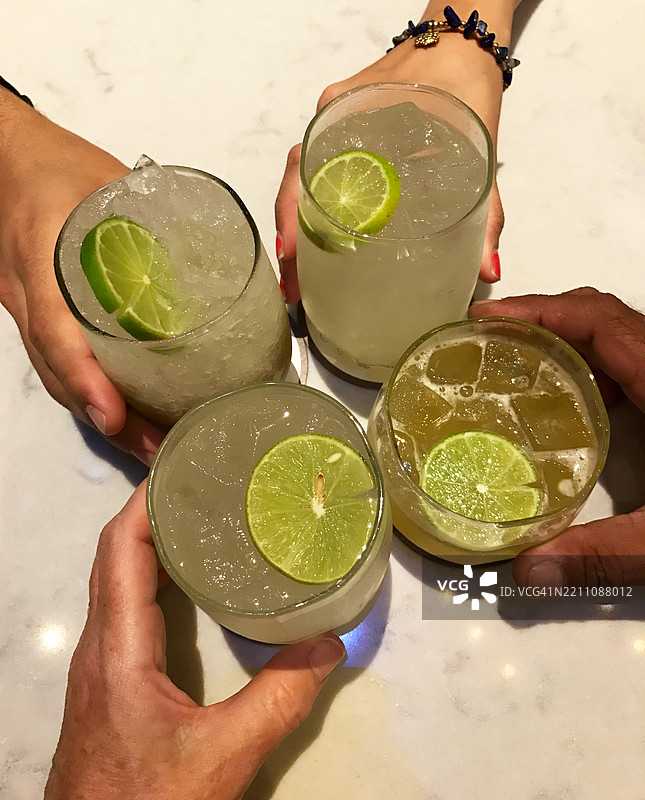 四个人举着莫吉托和迈泰鸡尾酒，俯视图庆祝干杯的特写镜头图片素材