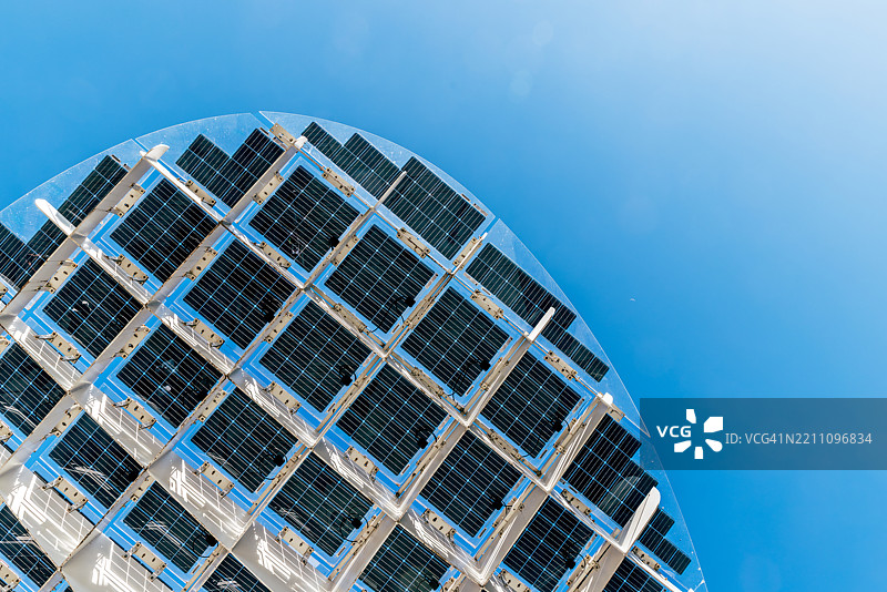 阳光明媚的日子里，低角度视图下的太阳能电池板与湛蓝的天空相映成趣图片素材