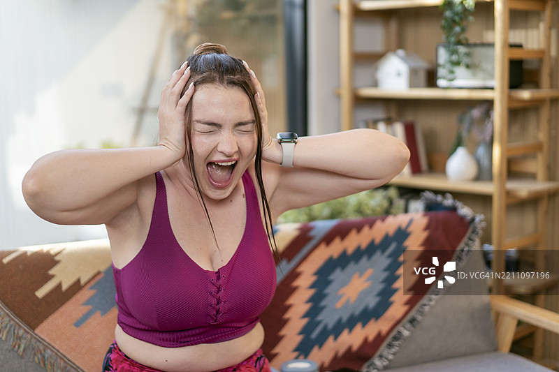 沮丧的超重女性坐在沙发上，不想锻炼图片素材