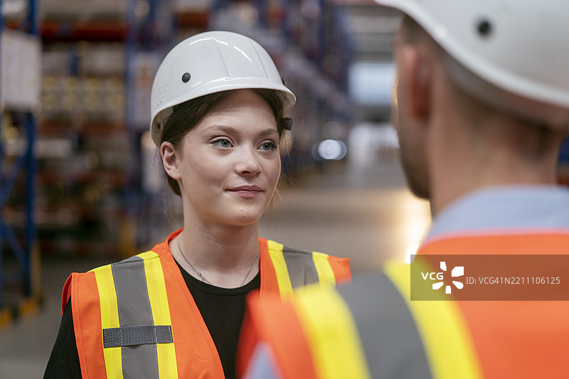仓库工人在配送仓库的货架过道与团队讨论。图片素材