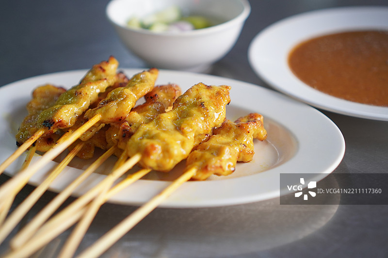 黄香料腌制的沙爹猪肉，穿在串上，烤至熟透，搭配酱汁和沙拉一起食用。图片素材