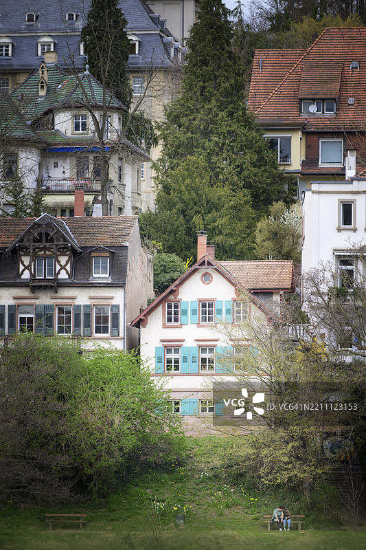 浪漫情侣坐在长椅上，背景是浪漫的德国海德堡风景图片素材