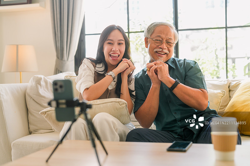 幸福的亚洲家庭，女儿和父亲一起在社交媒体平台上录制舞蹈，父亲和女儿们在家中快乐地跳舞并拍摄。图片素材