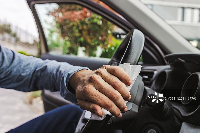 在户外用消毒湿巾清洁汽车方向盘的人图片素材