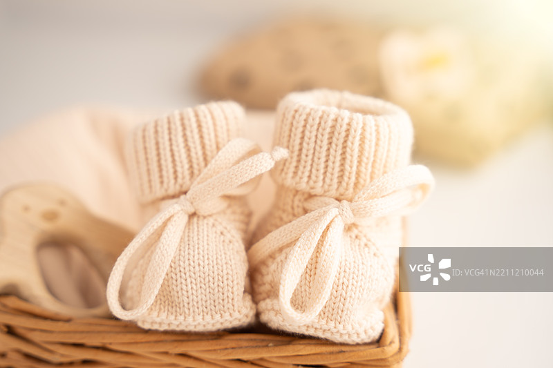 米色针织靴子放在一个装有婴儿配件的藤篮里图片素材